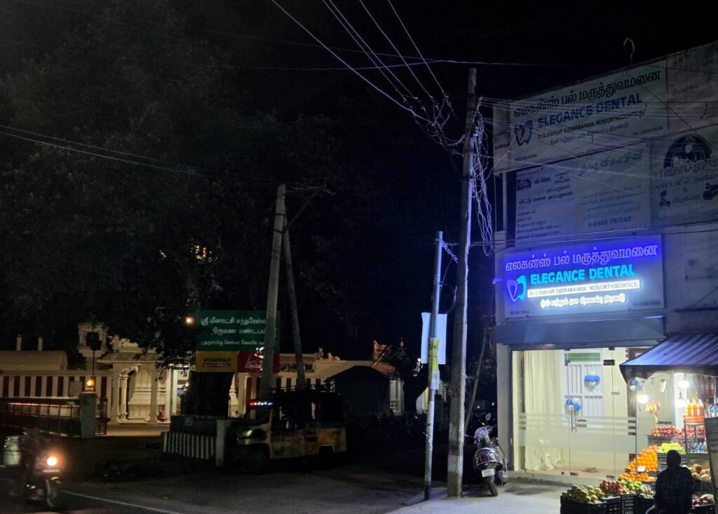 Nighttime exterior view of Elegance Dental & Multi-Speciality Clinic in Rajapalayam, featuring the brightly illuminated nameboard and entrance.